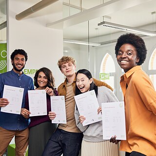 Gruppe glücklicher Kursteilnehmer, die stolz ihre Goethe-Zertifikate zeigen.